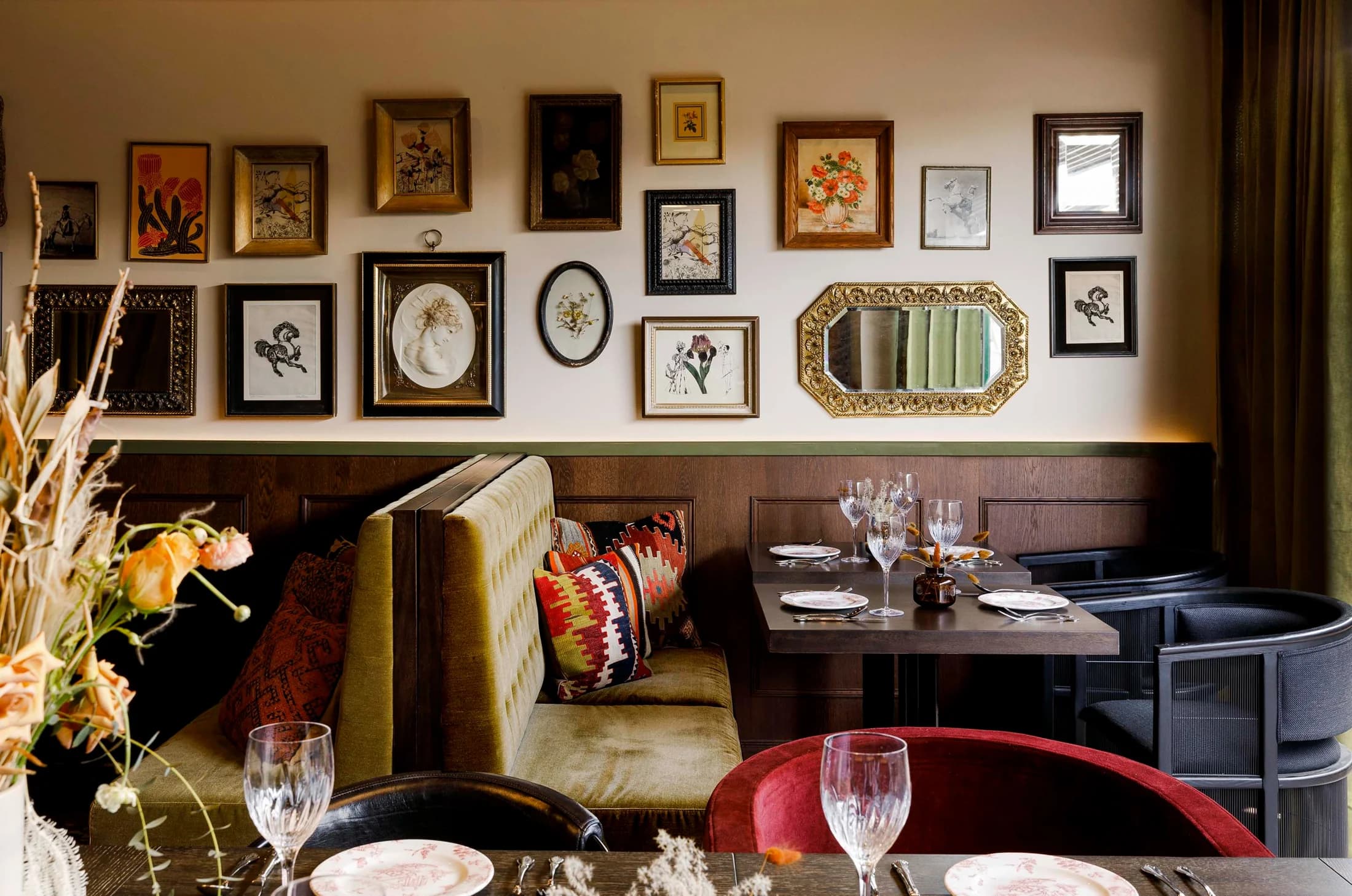 A warmly lit Wildflower dining room with set tables and framed artwork